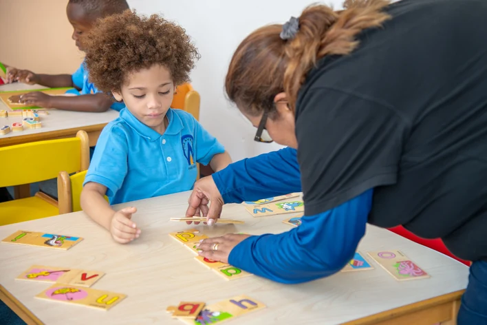 An educator building words with a child using letter cards